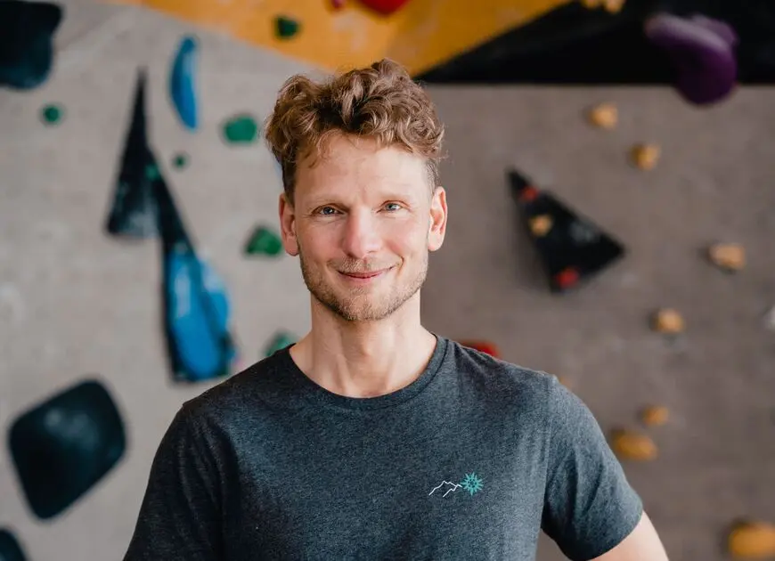 Ein Mann mit DAV-T-Shirt vor einer Boulderwand | © DAV