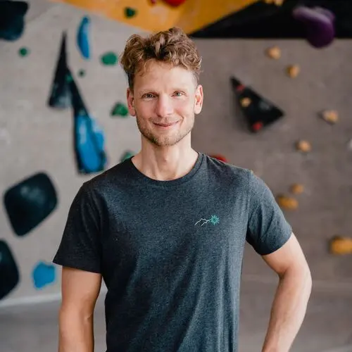 Ein Mann mit DAV-T-Shirt vor einer Boulderwand | © DAV